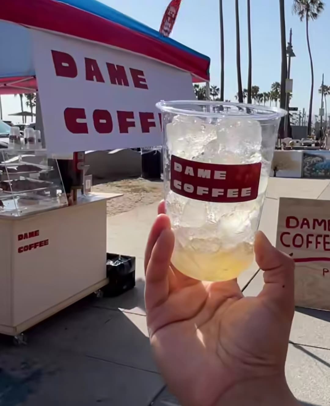 A Dame Coffee drink held in front of the cart at Venice Beach